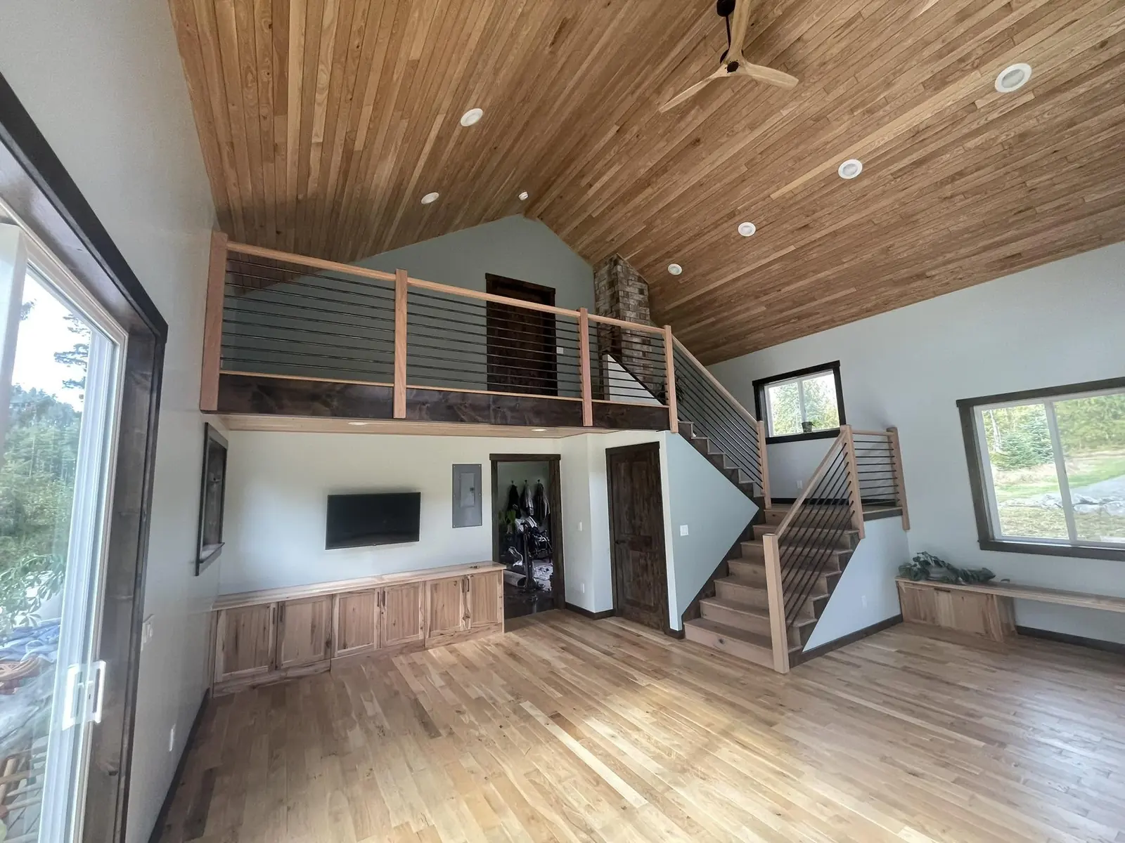 Home addition with a vaulted cedar ceiling and cable railing staircase by CKS Builders LLC
