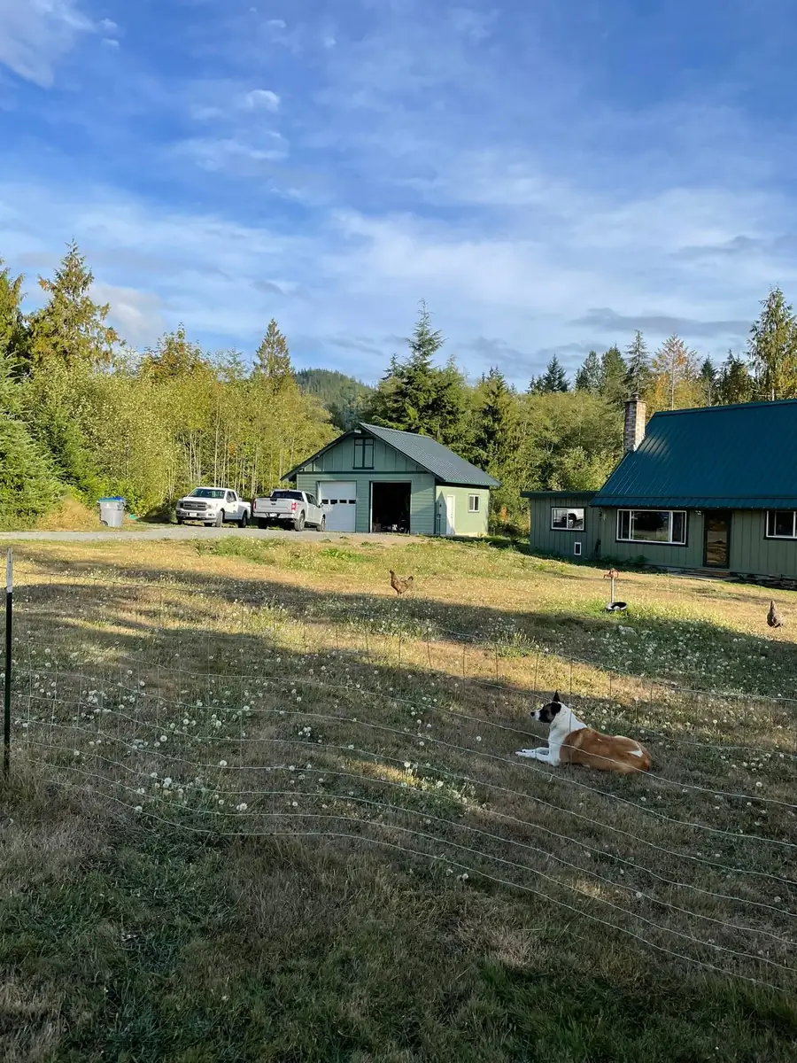 Open meadow behind a home with a detached secondary structure at the tree line, by CKS Builders LLC in Port Angeles, WA
