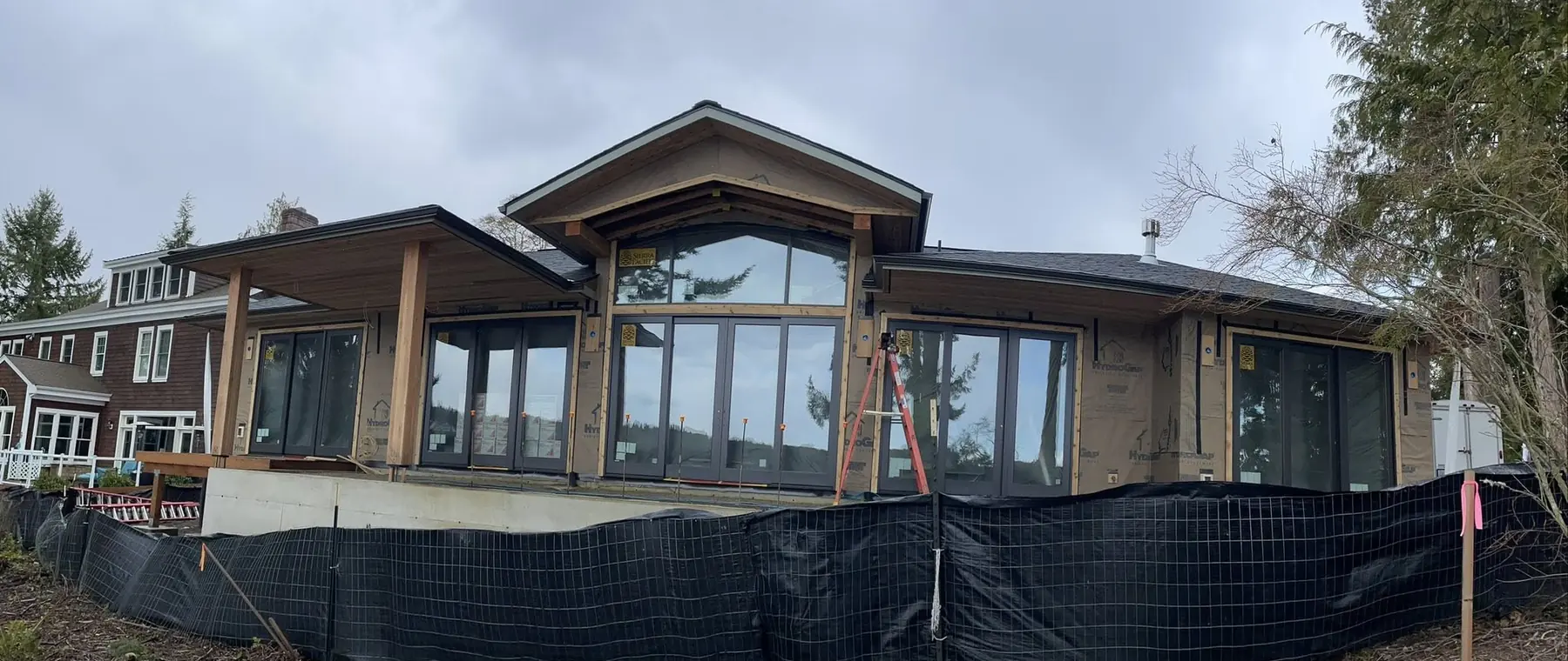 Long, low custom home with a timber-framed entry and a continuous wall of windows, built by CKS Builders LLC in Clallam County, WA