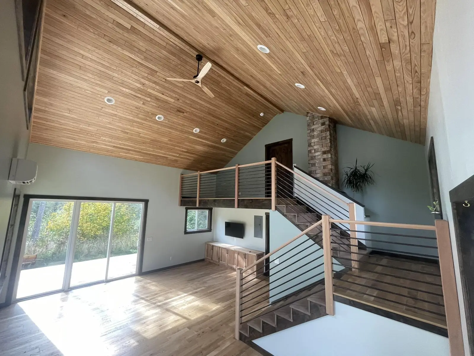 Open-concept living room with cable railing staircase after remodel in Port Angeles, WA
