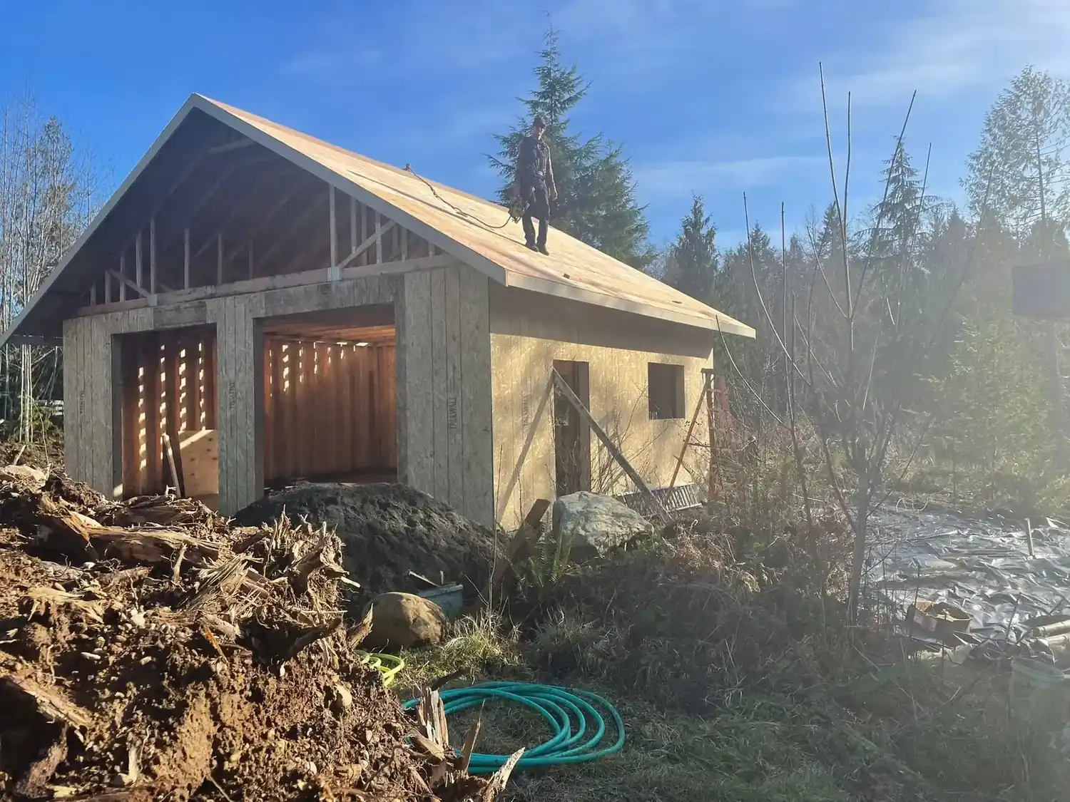 Addition framing and new roof structure going up on a wooded lot by CKS Builders LLC in Port Angeles, WA
