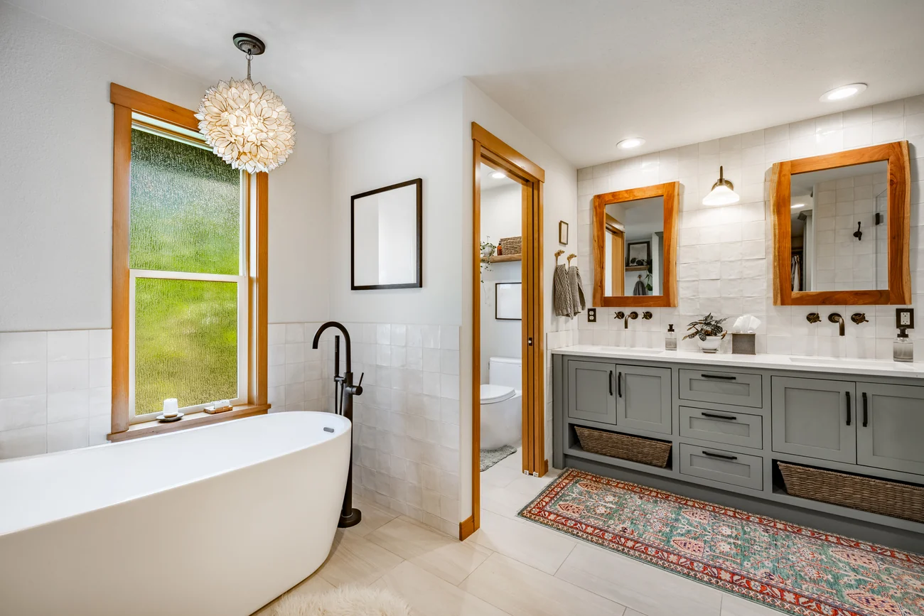 Double vanity with twin mirrors beside a freestanding tub
