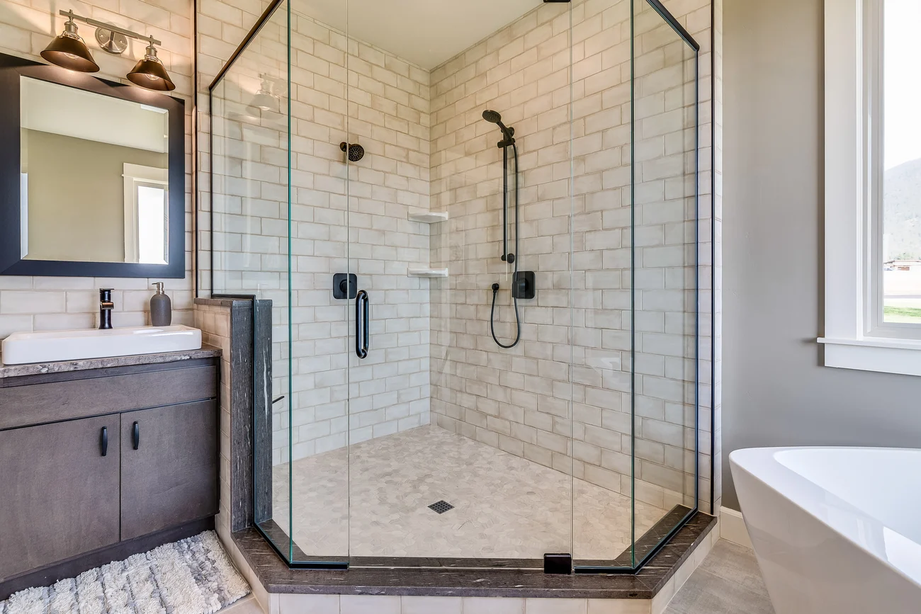 Corner glass walk-in shower with subway tile and black fixtures