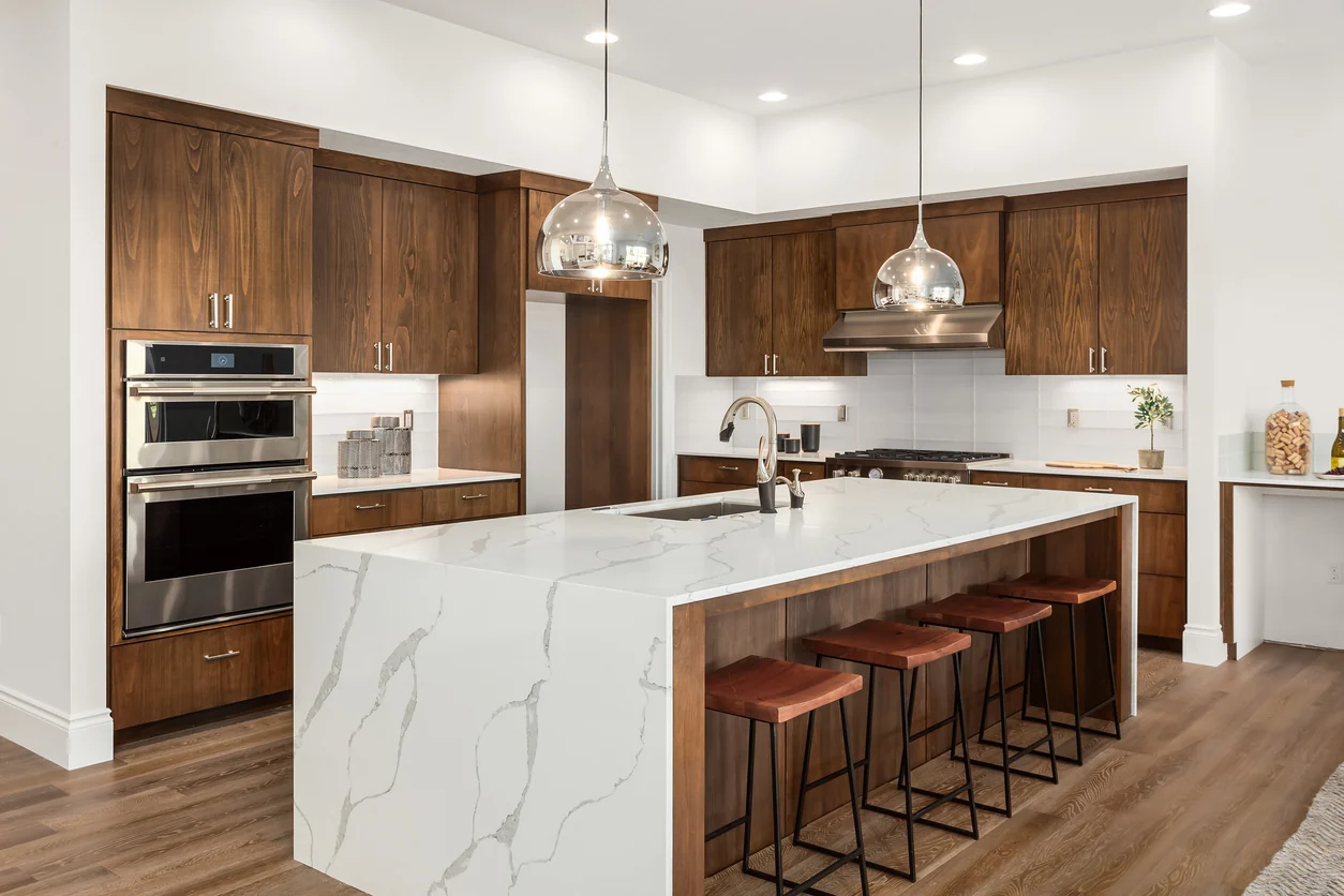 Open kitchen with a quartz waterfall island, bar seating, and walnut cabinetry