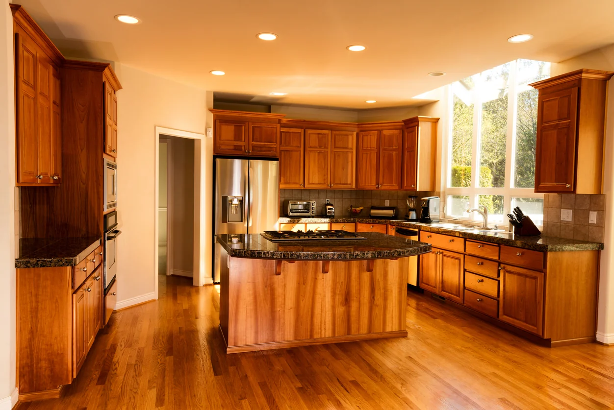 Expanded kitchen with an island, full cabinetry and an opening through to the adjoining room