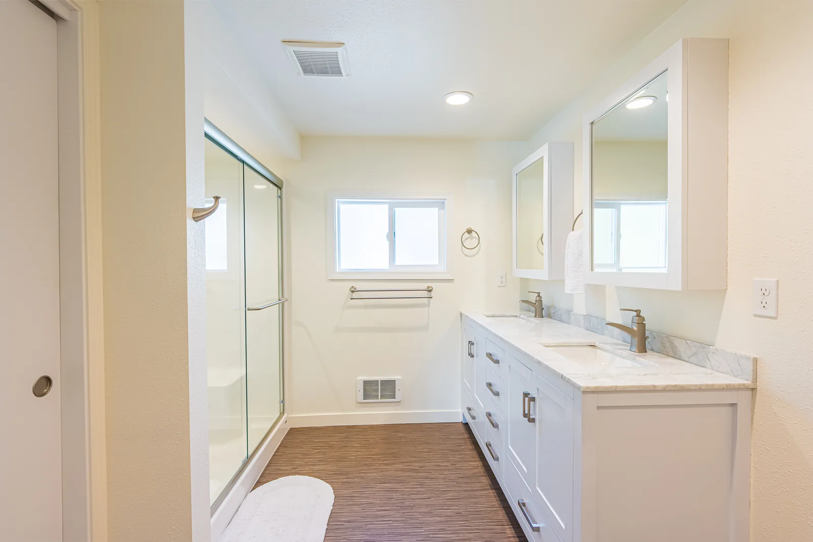 Remodeled bathroom with a sliding glass shower door beside a white double vanity, by CKS Builders LLC
