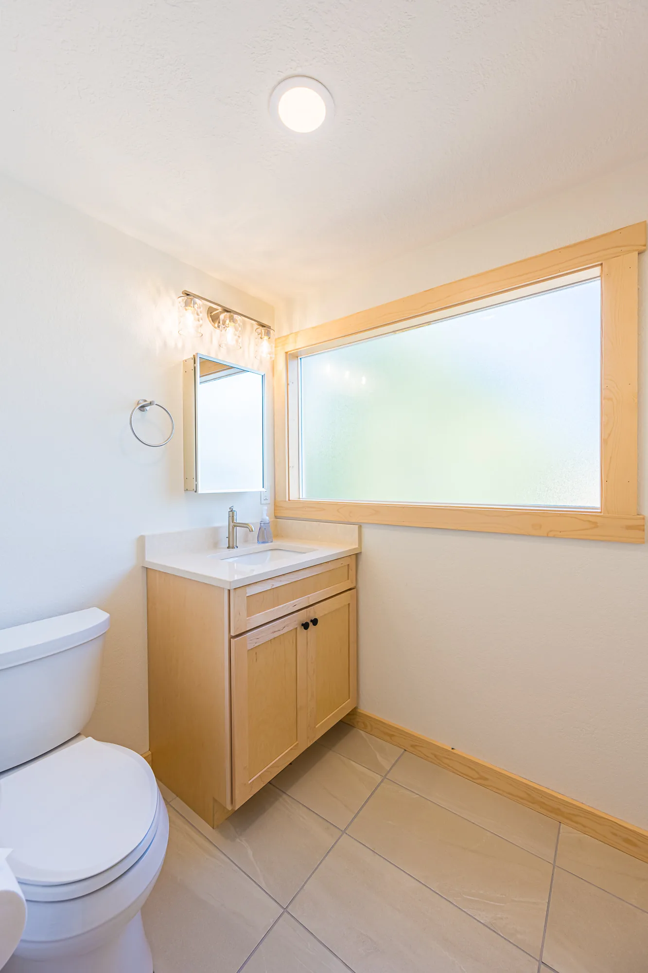 Small remodeled bathroom with a maple vanity, a framed mirror, and a wide window, by CKS Builders LLC