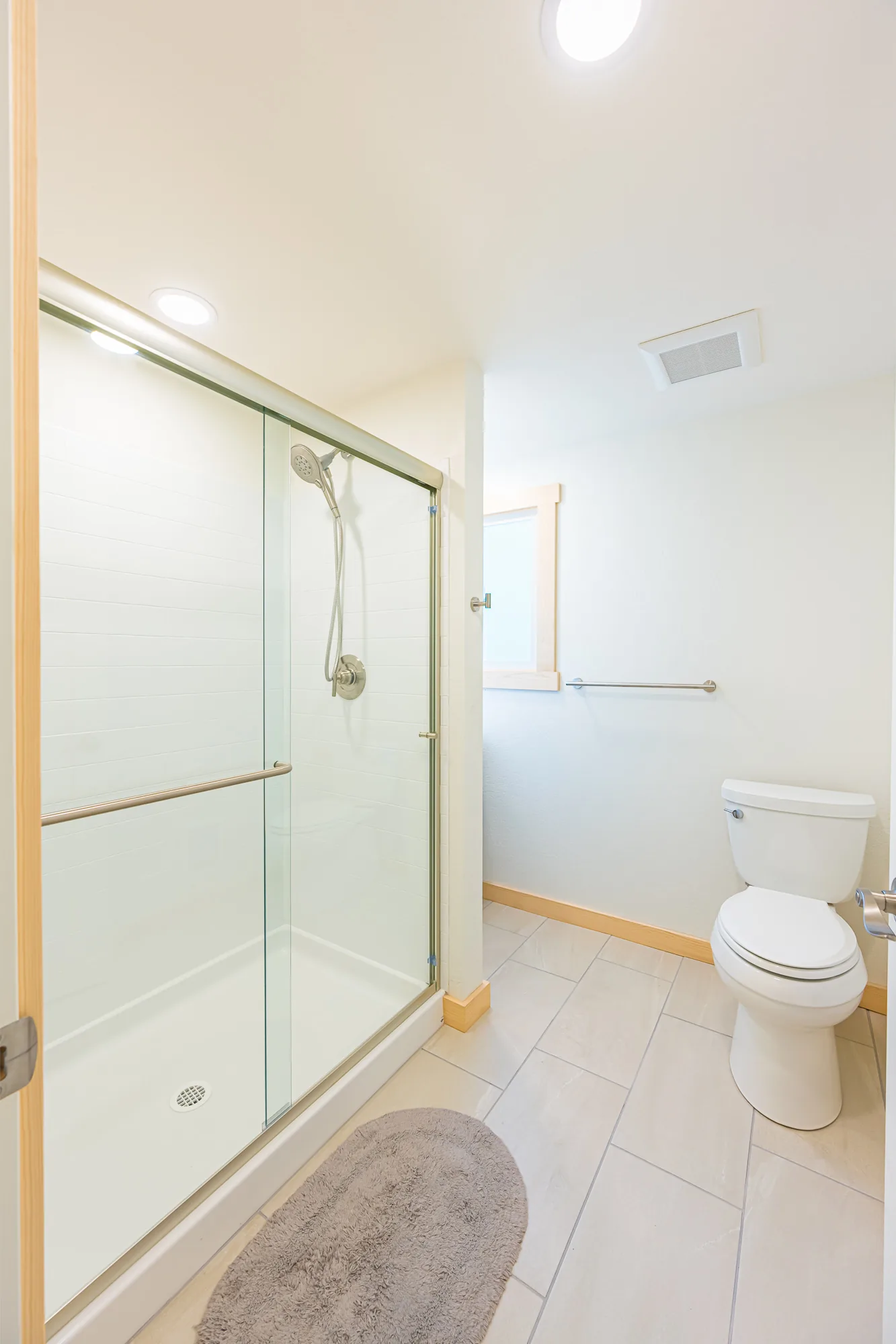 Remodeled bathroom with a glass shower enclosure and a light tile floor, by CKS Builders LLC