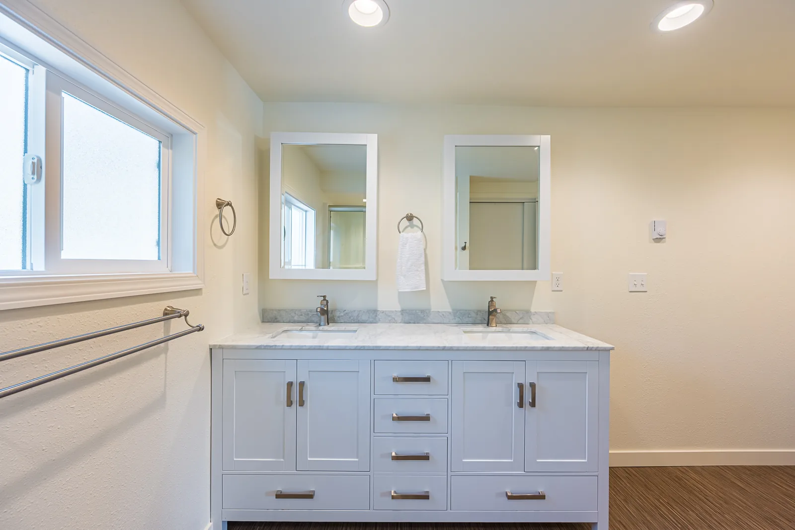 White double vanity with a stone-look top and two framed mirrors in a bathroom remodeled by CKS Builders LLC