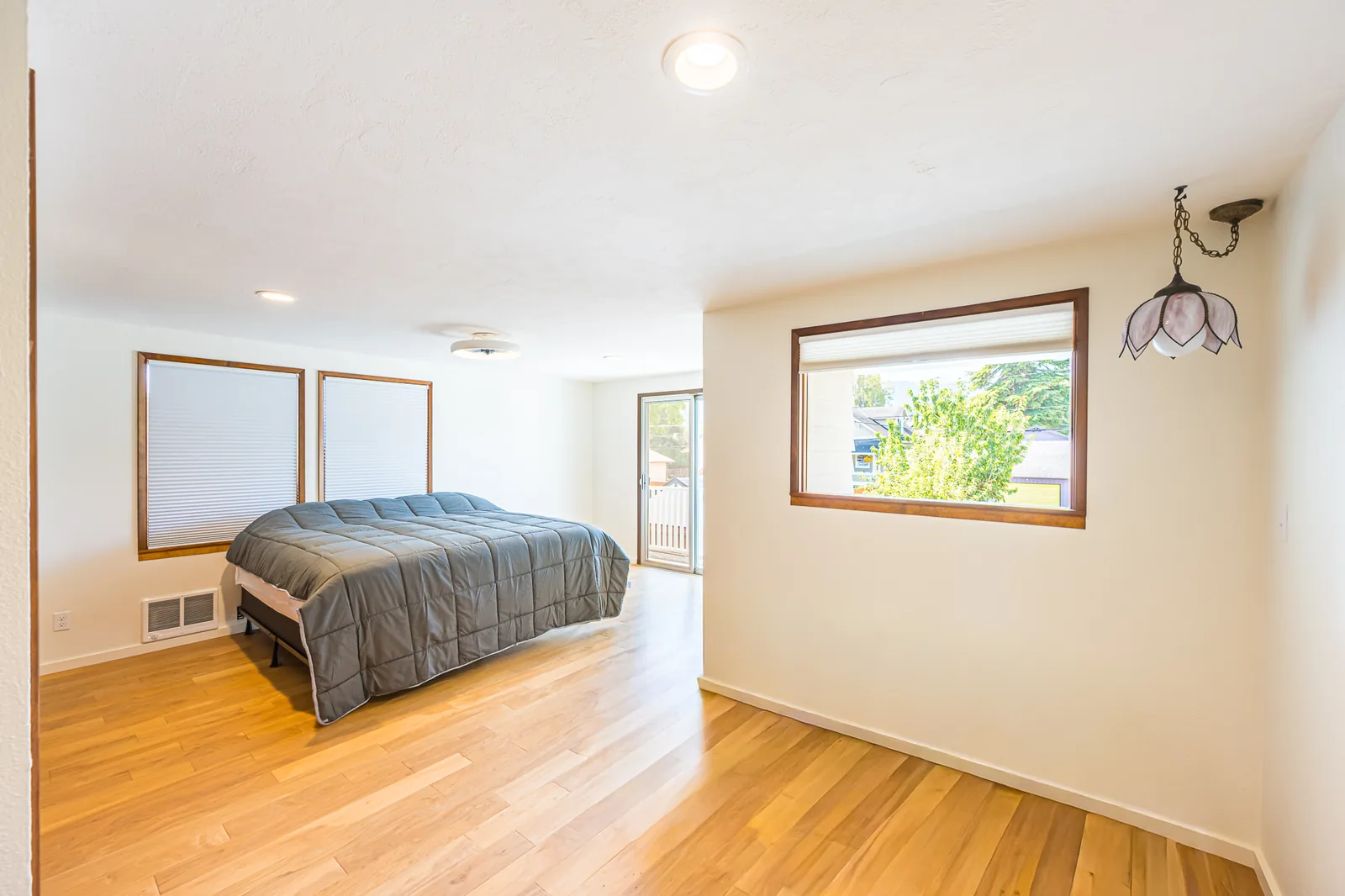 Bedroom with wood flooring and wood-trimmed windows in a home remodeled by CKS Builders LLC
