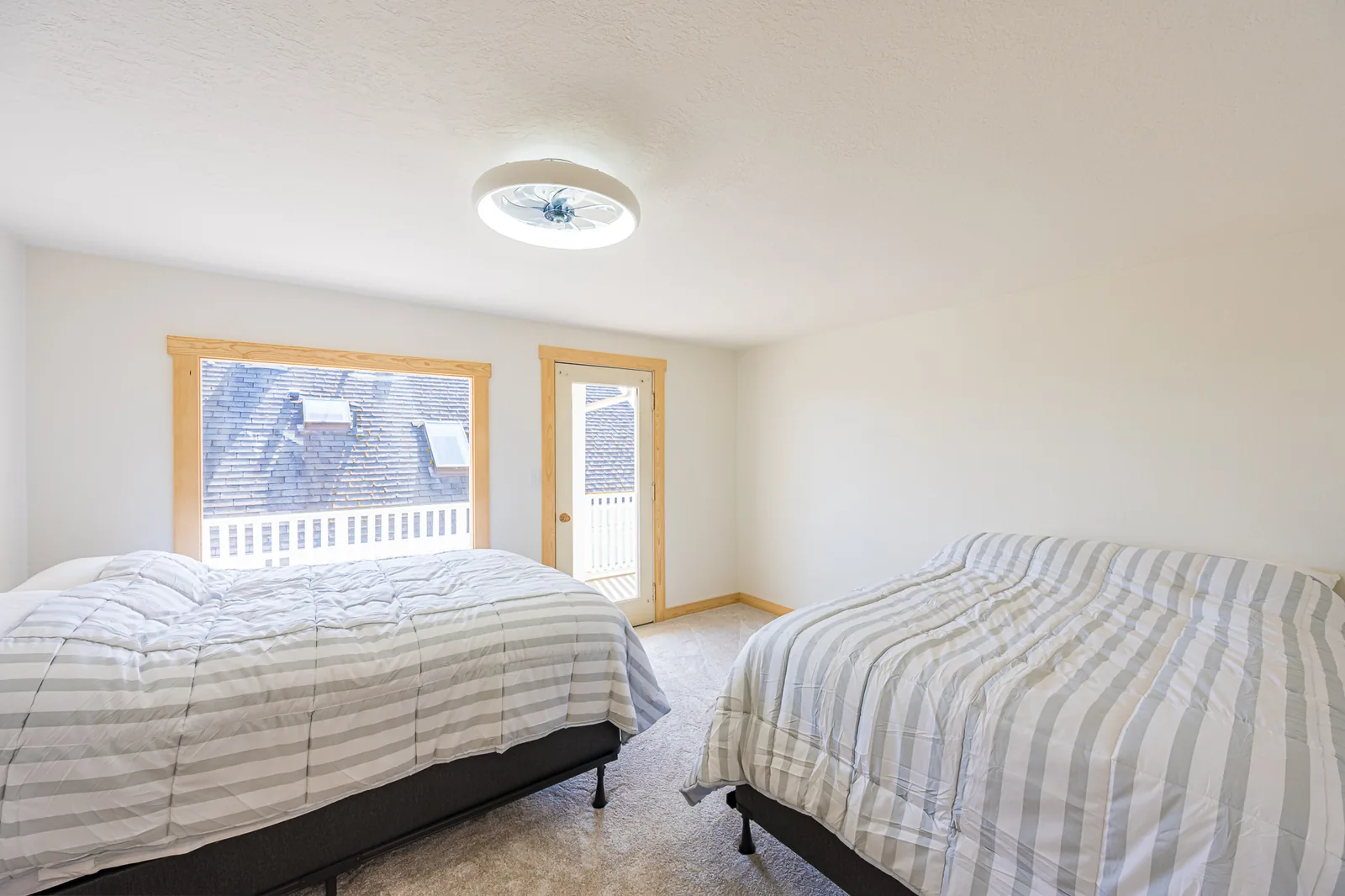 Carpeted guest bedroom with two beds and a door out to a deck in a home remodeled by CKS Builders LLC