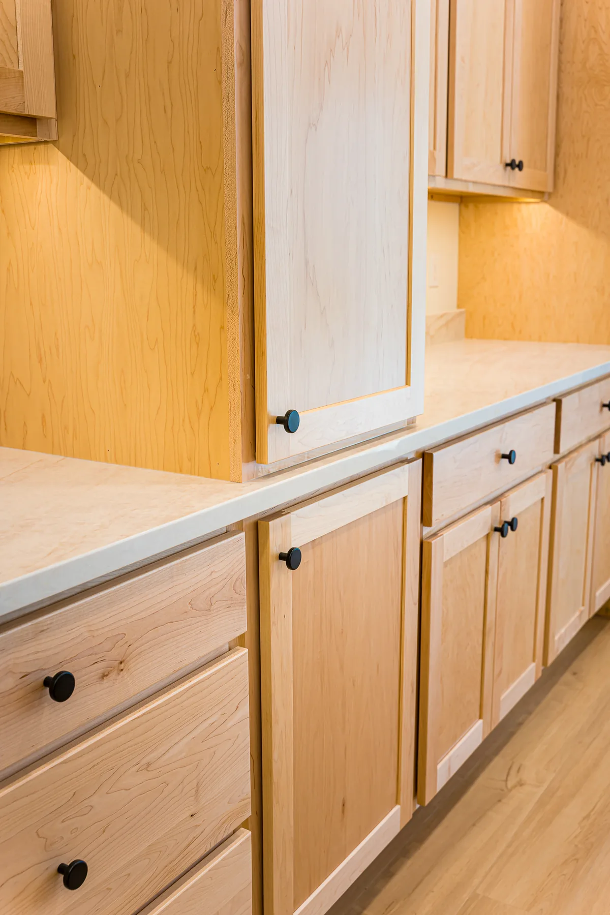 Maple kitchen cabinetry with black knobs and a light countertop, from a kitchen remodel by CKS Builders LLC