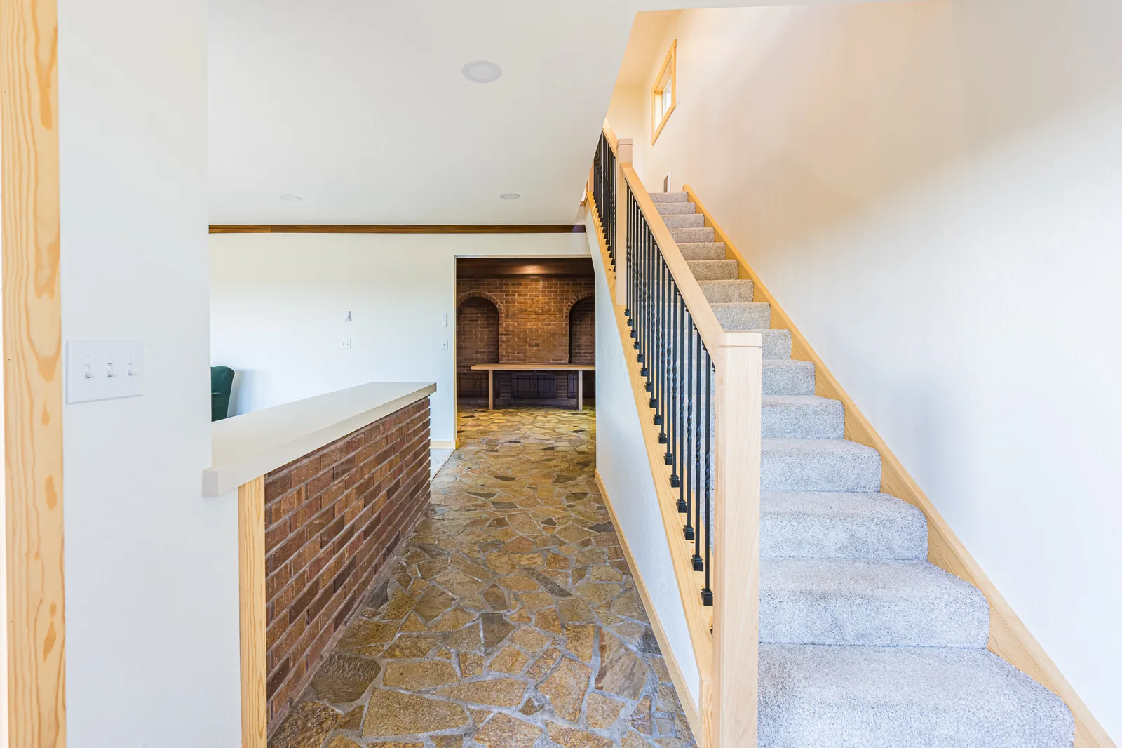 Flagstone entry floor beside a staircase with a maple and black metal railing in a home remodeled by CKS Builders LLC