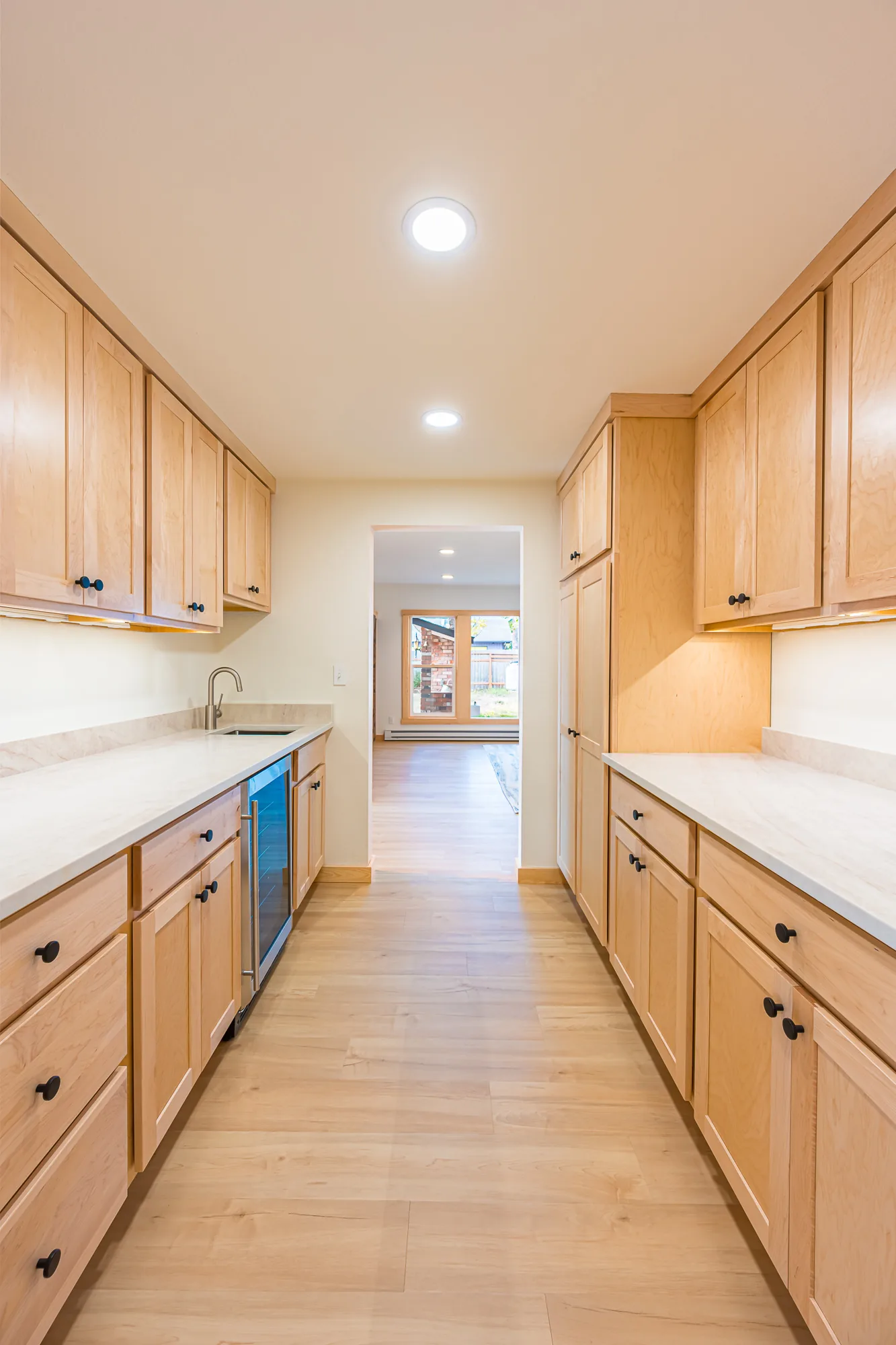 Galley kitchen with maple cabinets on both sides and a view down the hall, remodeled by CKS Builders LLC