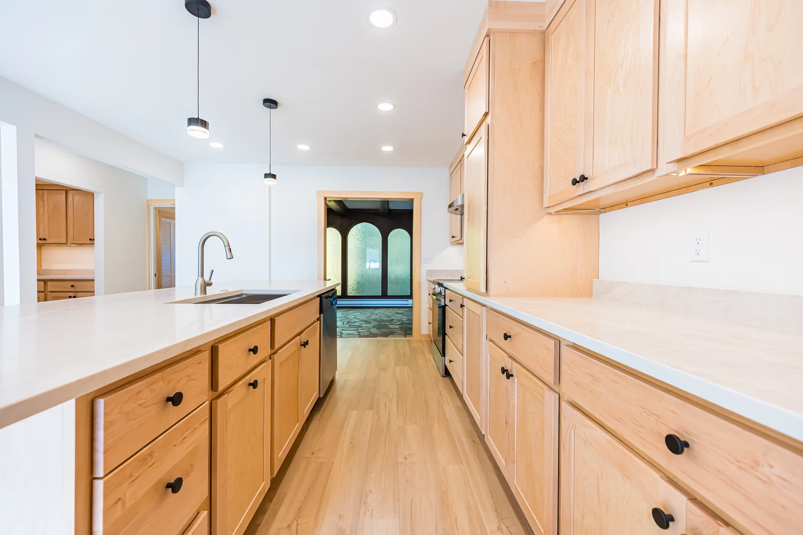 Kitchen island with an undermount sink, black pendant lights, and maple cabinets, remodeled by CKS Builders LLC