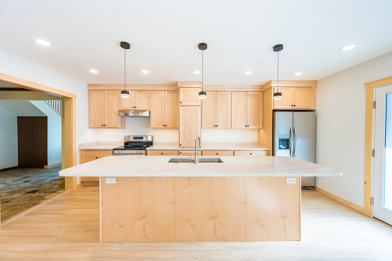 Remodeled kitchen with a large maple island, black pendant lights, and stainless appliances, by CKS Builders LLC
