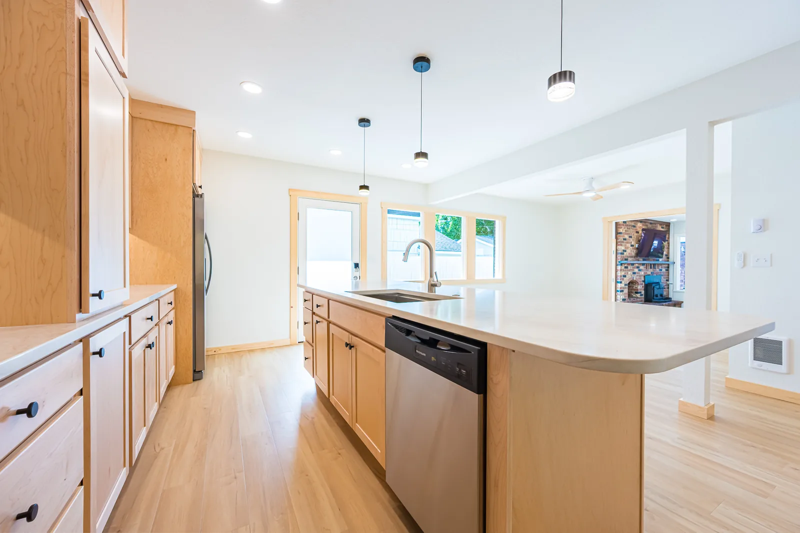 Kitchen with a long maple island open to the living and dining areas, remodeled by CKS Builders LLC