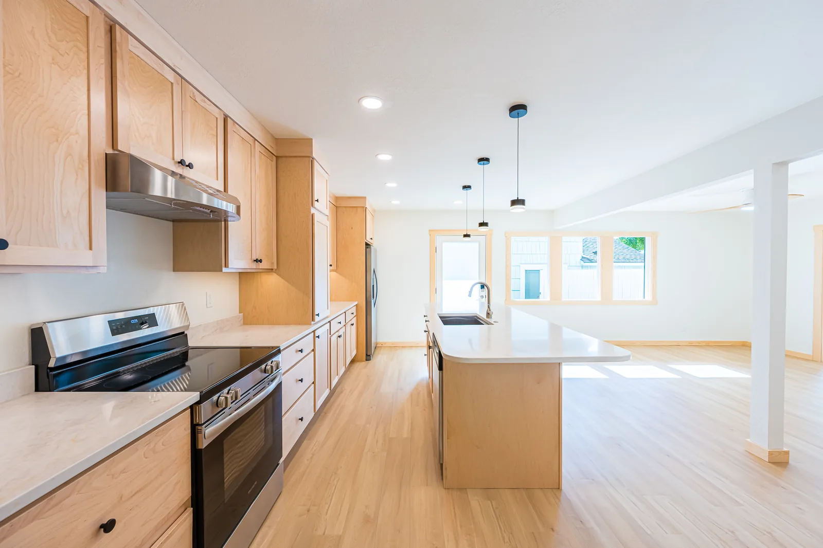 Kitchen range wall with maple cabinets, a stainless range and hood, and light countertops, remodeled by CKS Builders LLC