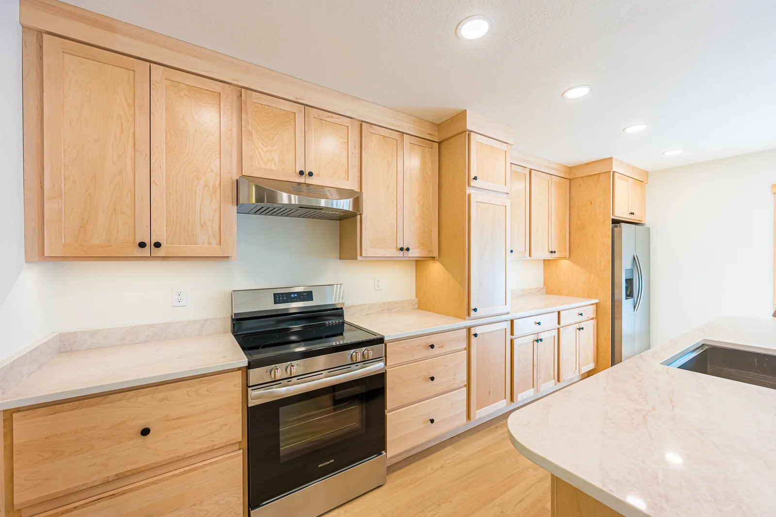 Maple kitchen cabinets around a stainless range and refrigerator, remodeled by CKS Builders LLC