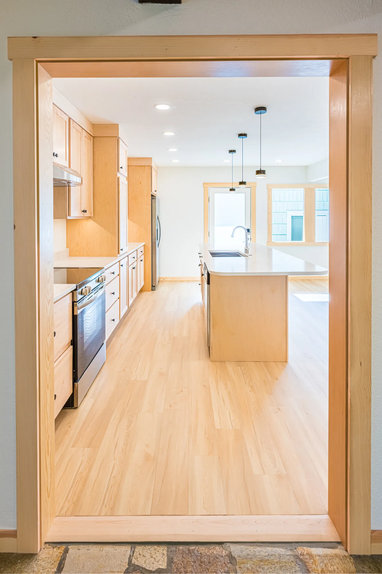 View through a wide wood-trimmed doorway into a remodeled maple kitchen, by CKS Builders LLC