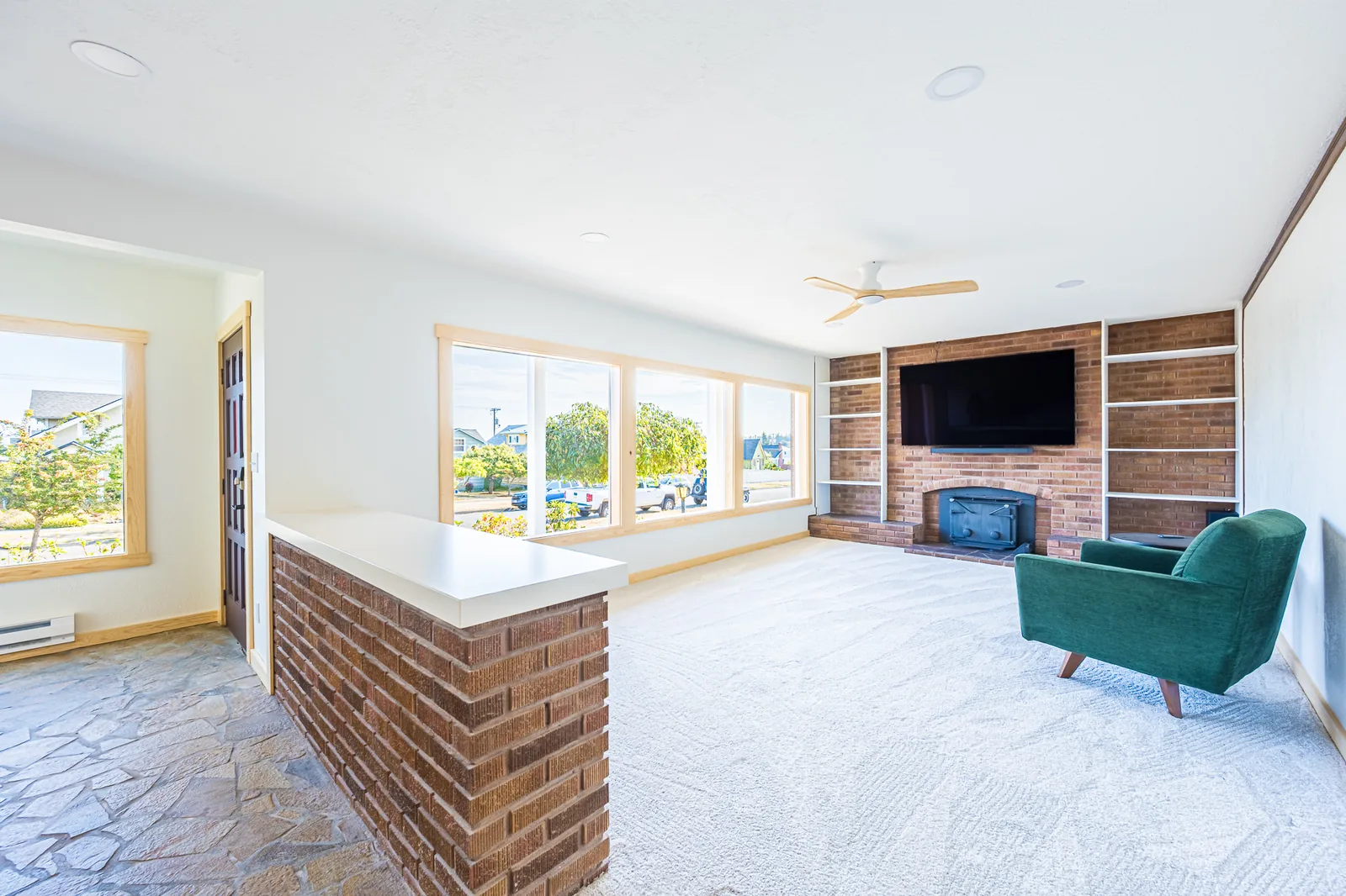 Living room with a brick fireplace and built-in shelving beside a flagstone entry and brick half wall, remodeled by CKS Builders LLC