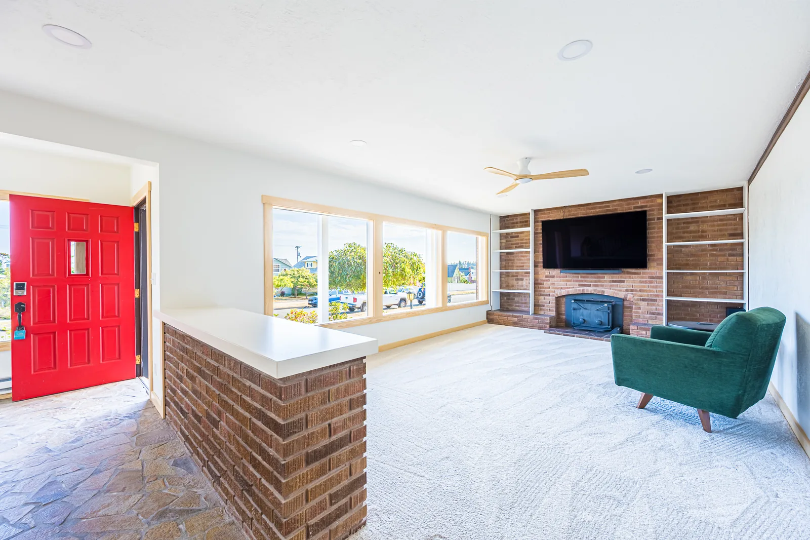 Living room with a red front door, flagstone entry, brick half wall, and brick fireplace wall, remodeled by CKS Builders LLC