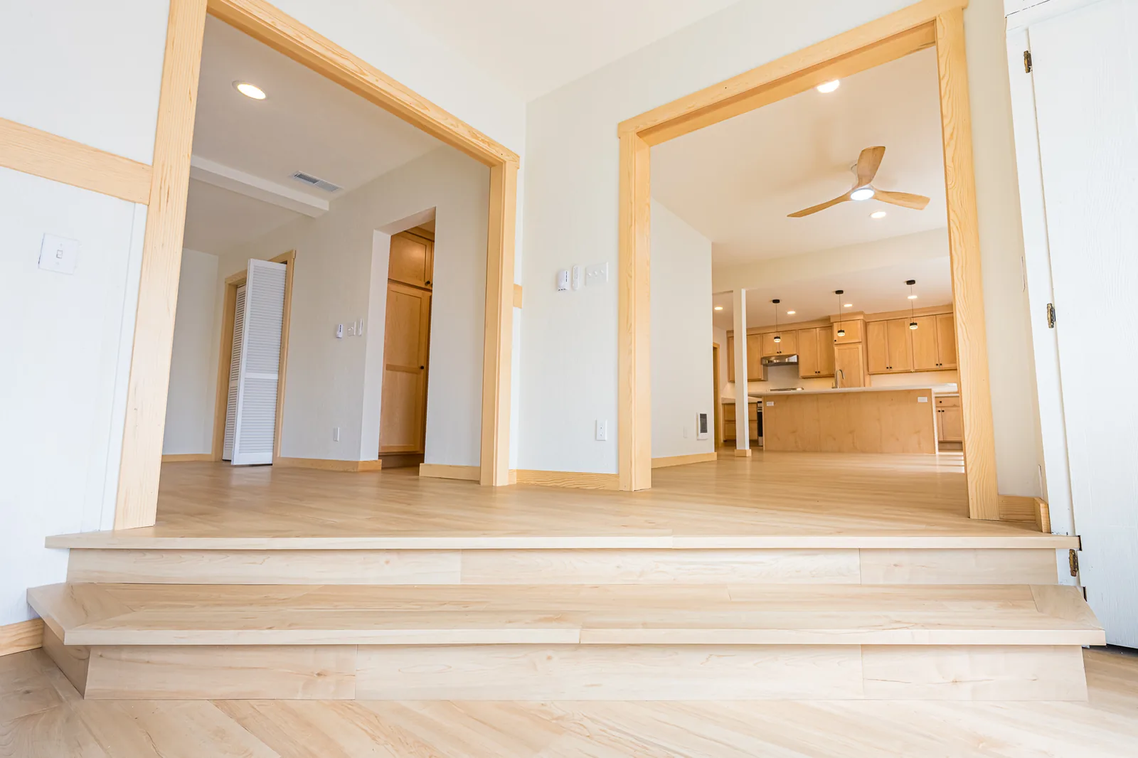 Wide steps up through two wood-trimmed openings toward the kitchen in a home remodeled by CKS Builders LLC