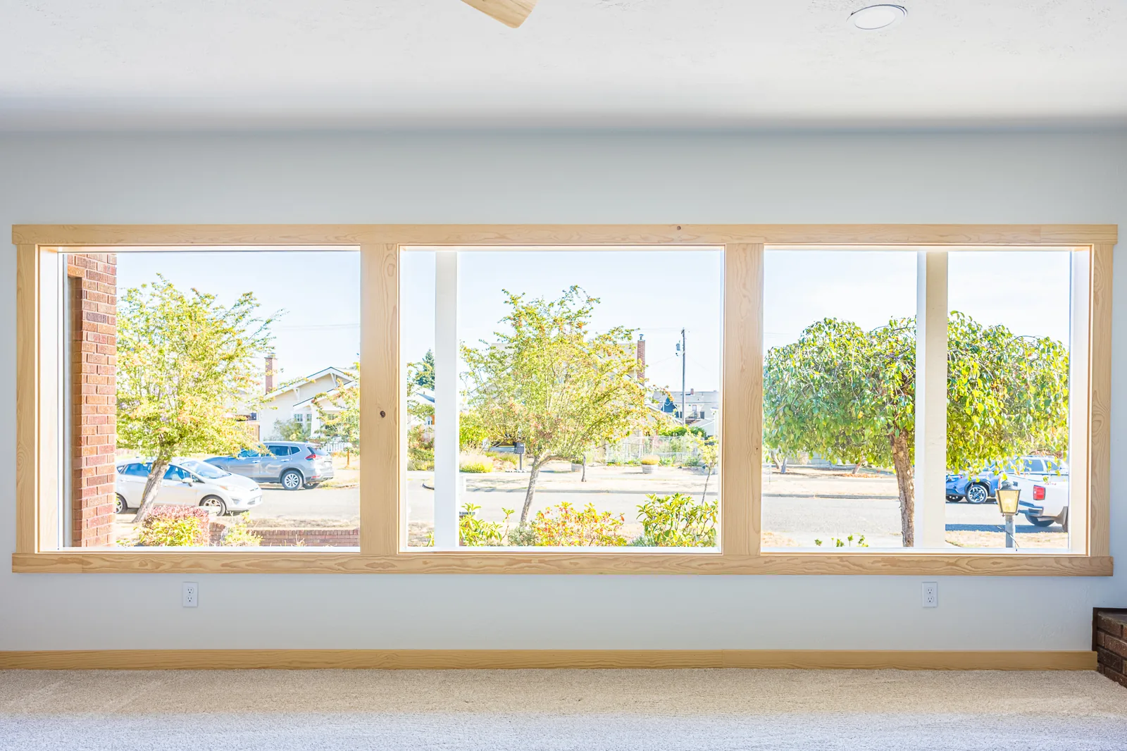 Wide wood-trimmed picture window looking out to the street from a living room remodeled by CKS Builders LLC