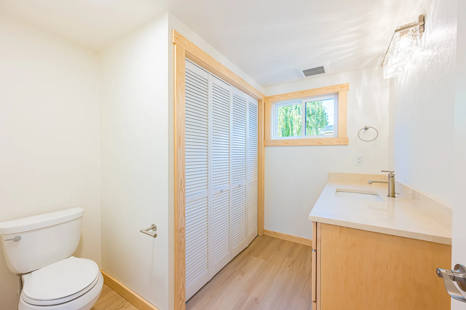 Half bath with a maple vanity, a light countertop, and a louvered closet door, remodeled by CKS Builders LLC