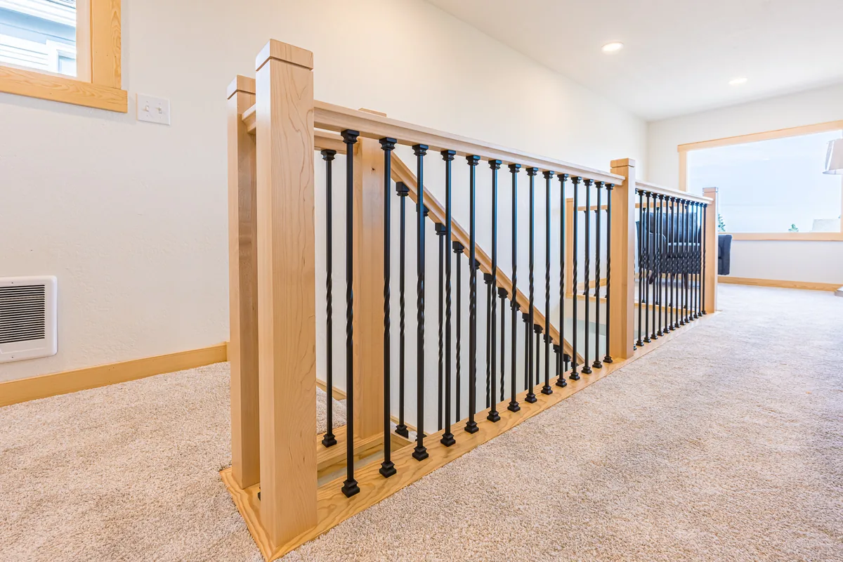 Maple stair railing with black metal balusters along an upstairs landing, built during a remodel by CKS Builders LLC