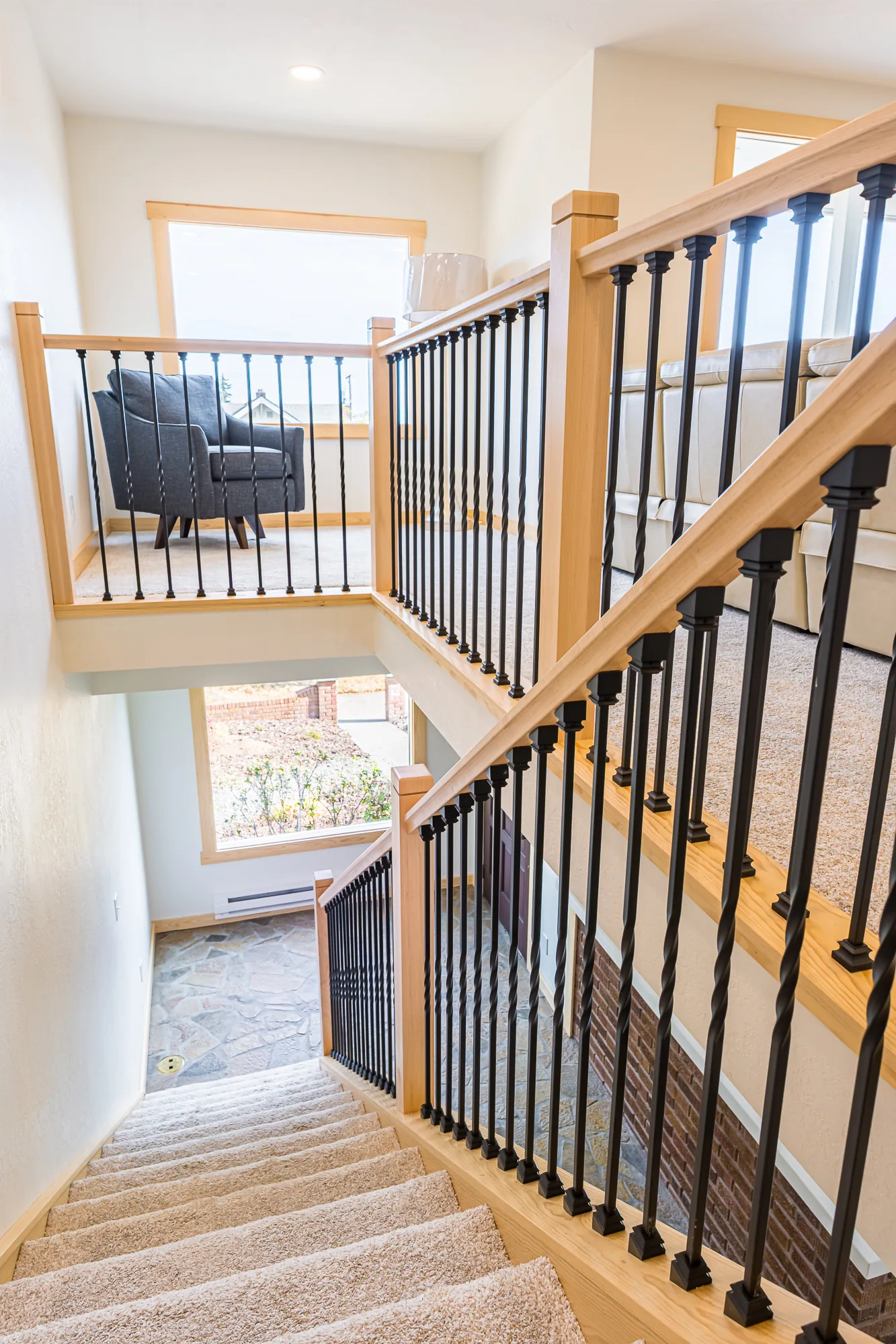 Looking down a carpeted staircase with maple and black metal railings, remodeled by CKS Builders LLC