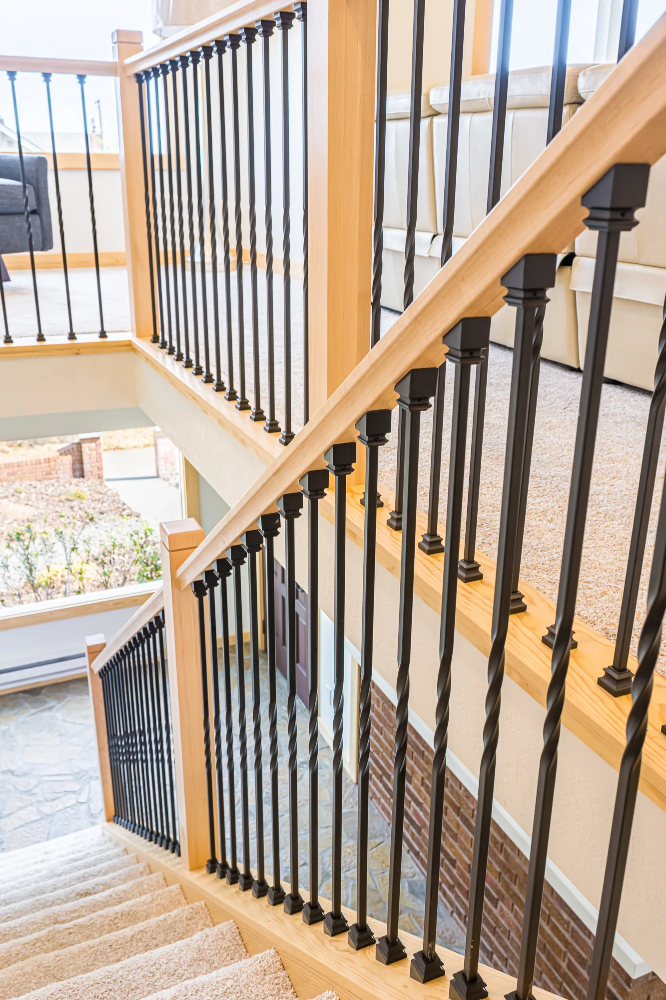 Maple posts and black metal balusters framing a staircase in a home remodeled by CKS Builders LLC