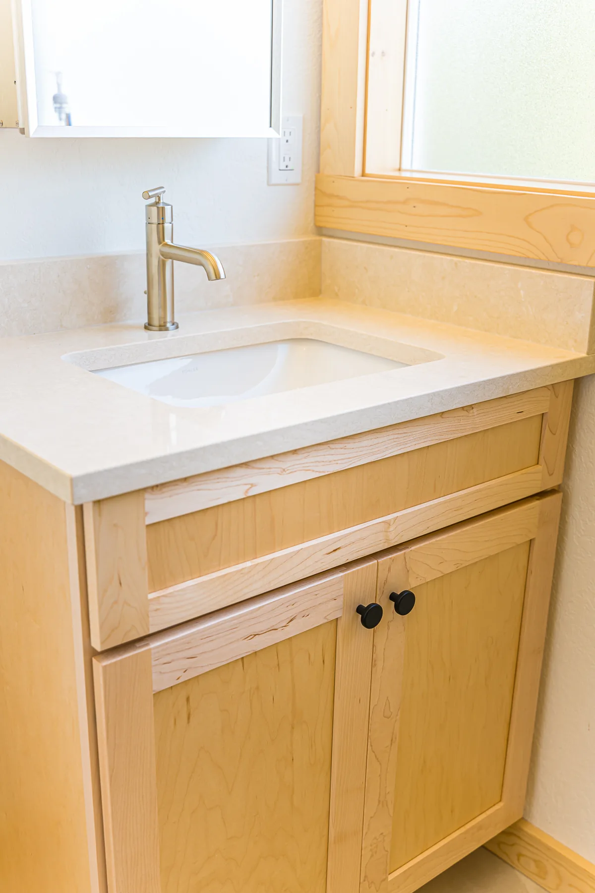 Maple bathroom vanity with an undermount sink and brushed faucet, remodeled by CKS Builders LLC